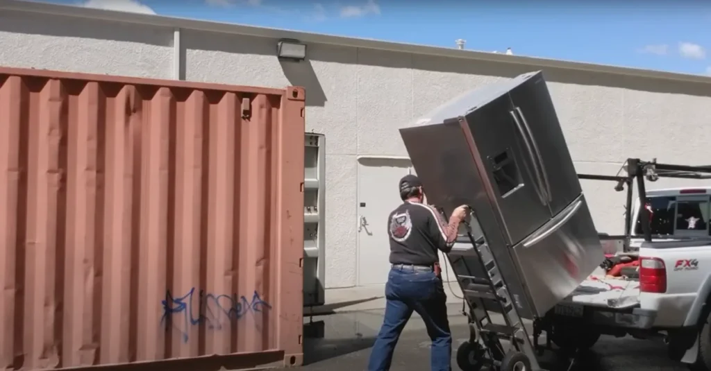 Apartment Movers 17 Mover wheeling a refrigerator past a storage container
